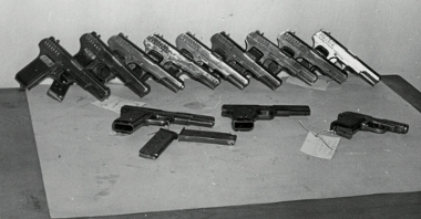Czarno-biała fotografia wykonana w 1956 roku. Na fotografii kilkanaście sztuk pistoletów, które zostały wykorzystane przez demonstrantów 28 czerwca 1956 roku podczas walk pod Wojewódzkim Urzędem do spraw Bezpieczeństwa. Fotografia była materiałem dowodowym w aktach śledczych procesów.