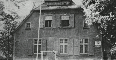 Czarno-biała fotografia przedstawiająca budynek posterunku Milicji Obywatelskiej w Mosinie w 1956 roku.