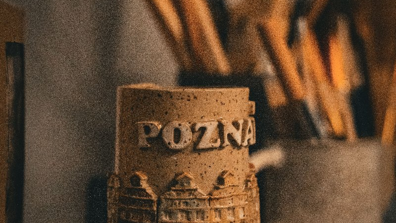 Na fotografii jest ulepiony z gliny kubek, który jest już ozdobiony nazwą miasta oraz budynkiem