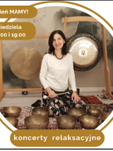 Kobieta w białej bluzce siedzi na dywanie. Przed nią stoją misy i gongi do grania.