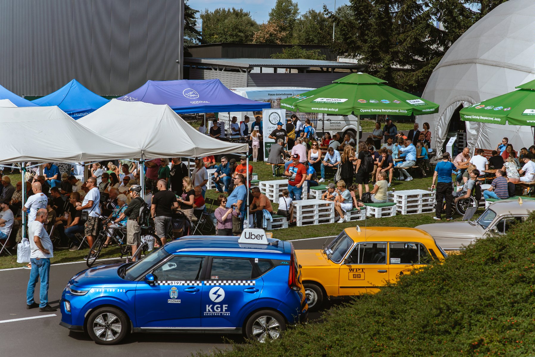 Zdjęcie podczas imprezy "Poznański Taksówkarz Roku 2023" wykonane na torze Hipodrom Poznań, na zdjęciu widoczni są uczestnicy wydarzenia, pojazdy.