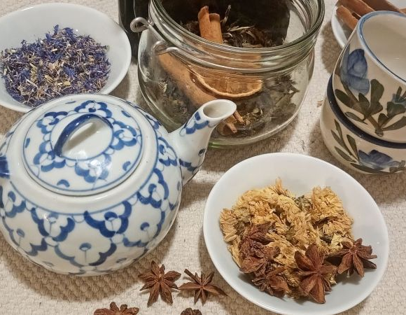 Różne mieszanki herbat w miseczkach, słoiczkach, obok imbryk i herbaciane filiżanki.