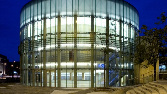 Podświetlony nocą budynek sali koncertowej Akademii Muzycznej o okrągłym kształcie.