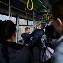 Dwóch mężczyzn prezentuje jak samoobronić się w tramwaju. pokazowi przyglądają się uczestnicy.