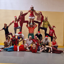 Grupa osób w świątecznych strojach tworzy piramidę ze swoich ciał.