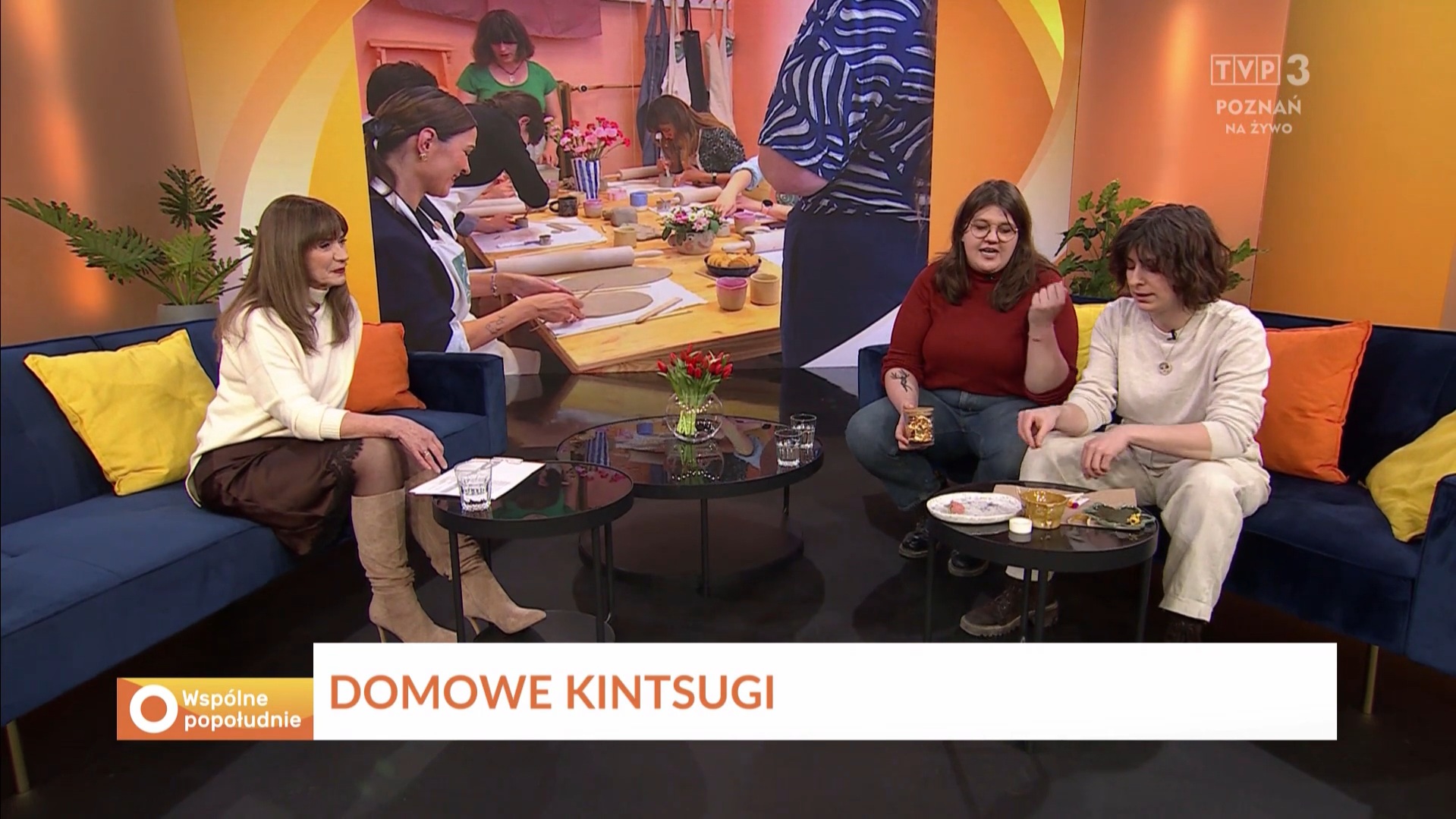 Trzy osoby siedzą na kanapach w studiu telewizyjnym, rozmawiając na temat aktualnych wydarzeń.