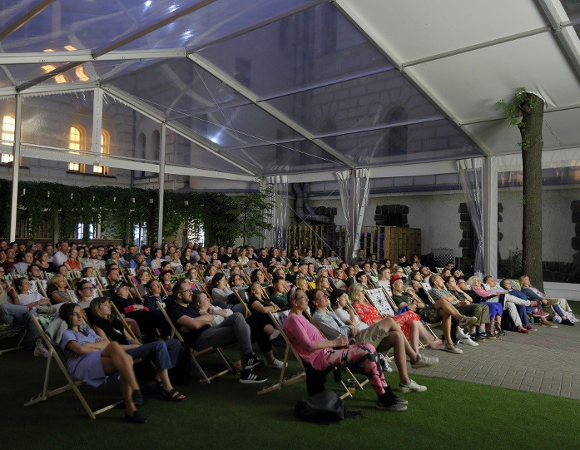 Widzowie będą mieli okazję obejrzeć jeszcze trzy filmy. Widownia siedzi na leżakach i ogląda film na ekranie, którego nie widać w kadrze. Całe miejsce jest zakryte dachem z przezroczystymi elemntami. Przez dach przechodzi drzewo.