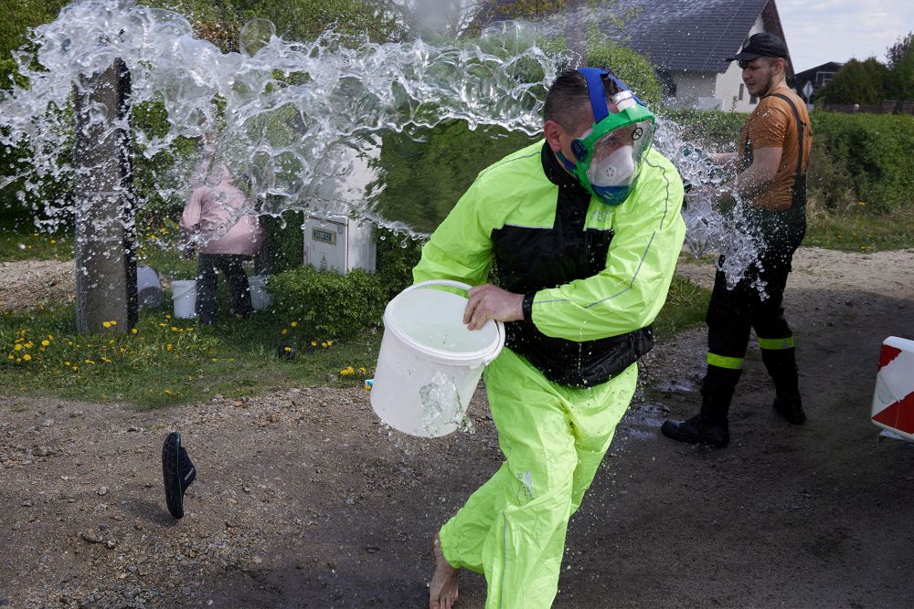 Wszędzie leje się woda, nawet na obiektyw. Kilku mężczyzn w koszulkach lub bez koszulek oblewa się wiadrami pełnymi wody.