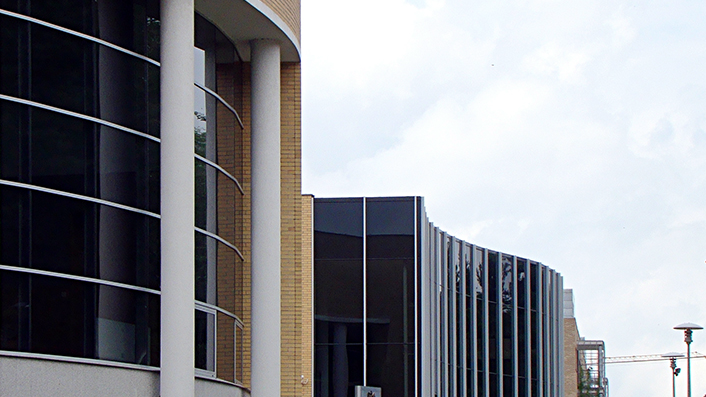 Galeria zdjęć przedstawia budynek Wydziału Matematyki i Informatyki UAM o biało-żółtej elewacji. Obiekt otoczony jest zielenią.