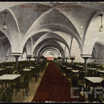 To jest zdjęcie dużego stołu do jadalni. Widać na nim oznaki starości. Na środku sali znajduje się czerwony dywan.