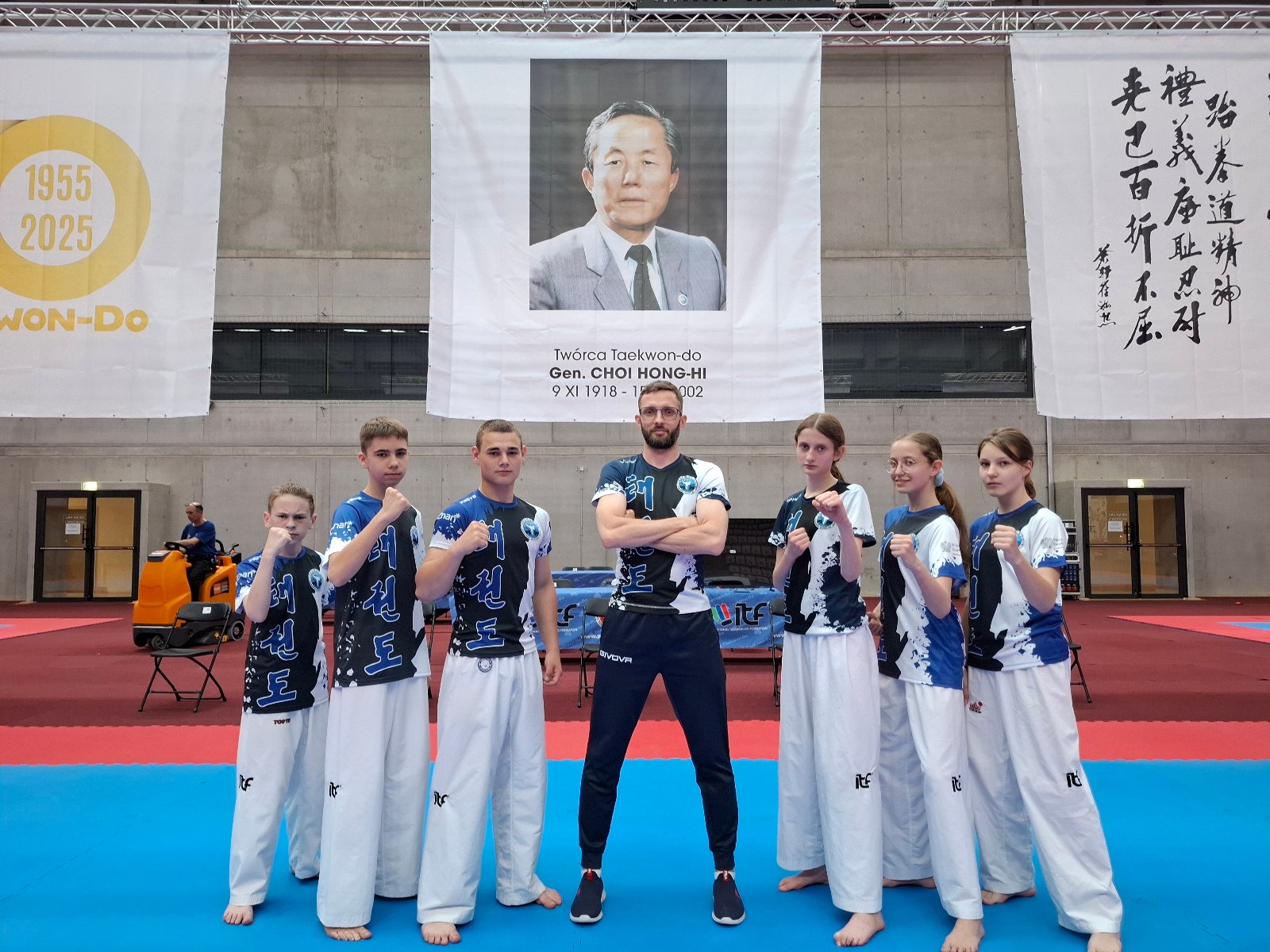 Zawodnicy PSKT na MP kadetów w Taekwon-do ITF Zawodnicy PSKT na MP kadetów w Taekwon-do ITF - w środku stoi trener, a po lewej stronie 3 zawodników, zaś po prawej 3 zawodniczki w bojowych pozach. Wszyscy mają niebiesko-czarno-białe koszulki i białe spodnie, zaś trener ma niebieskie spodnie. W tle arena walk oraz zdjęcie założyciela dyscypliny