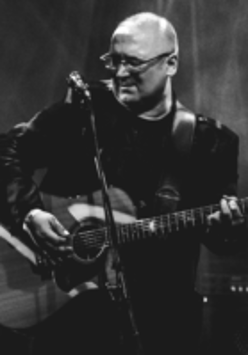 Na czarno-białym zdjęciu postać Roberta Kasprzyckiego z gitarą.