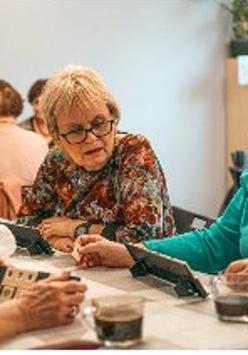 Grupa kobiet gra w Rummikub przy kawie.