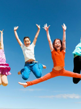 Dzieci skaczące w góre na tle nieba.