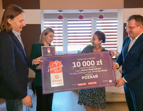 zdjęcie przedstawia 4 osoby trzymające duży czek z napisem 10 tysięcy złotych