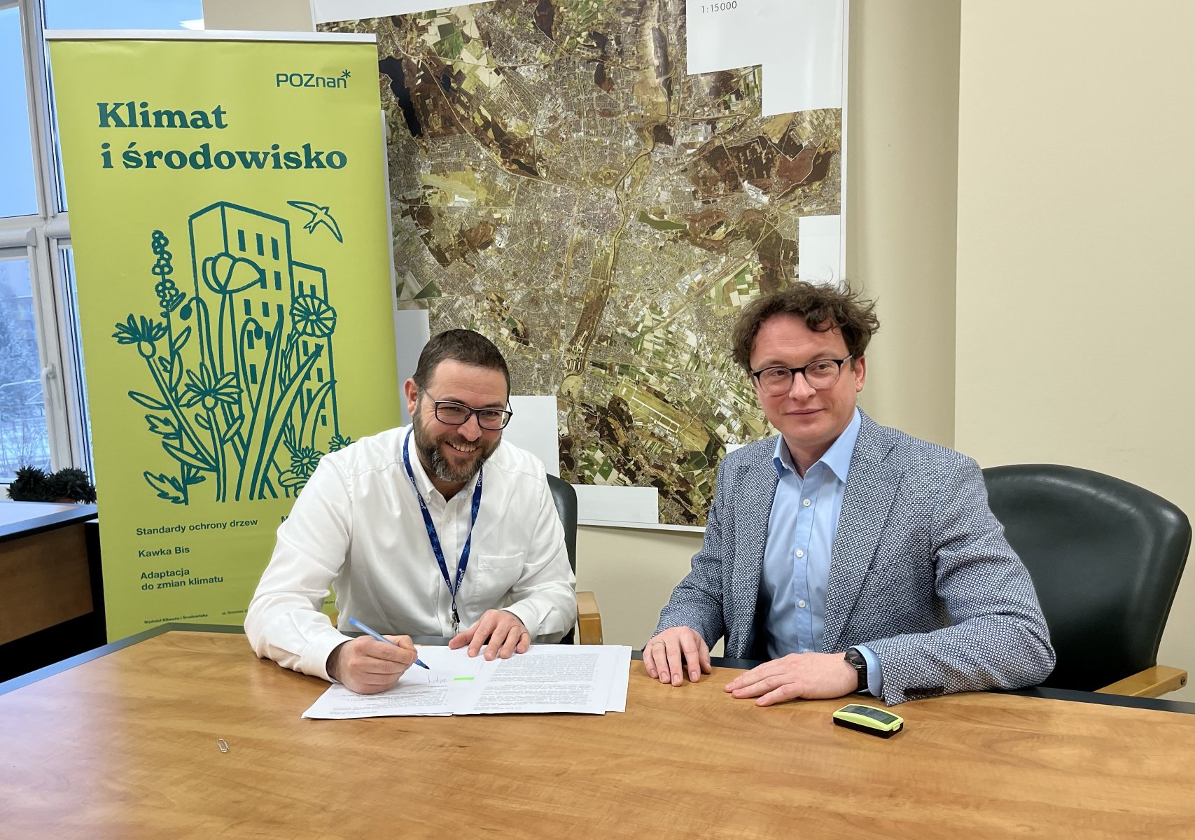 Zdjęcie przedstawiające dwóch mężczyzn podpisujących umowę na wykonywanie badań