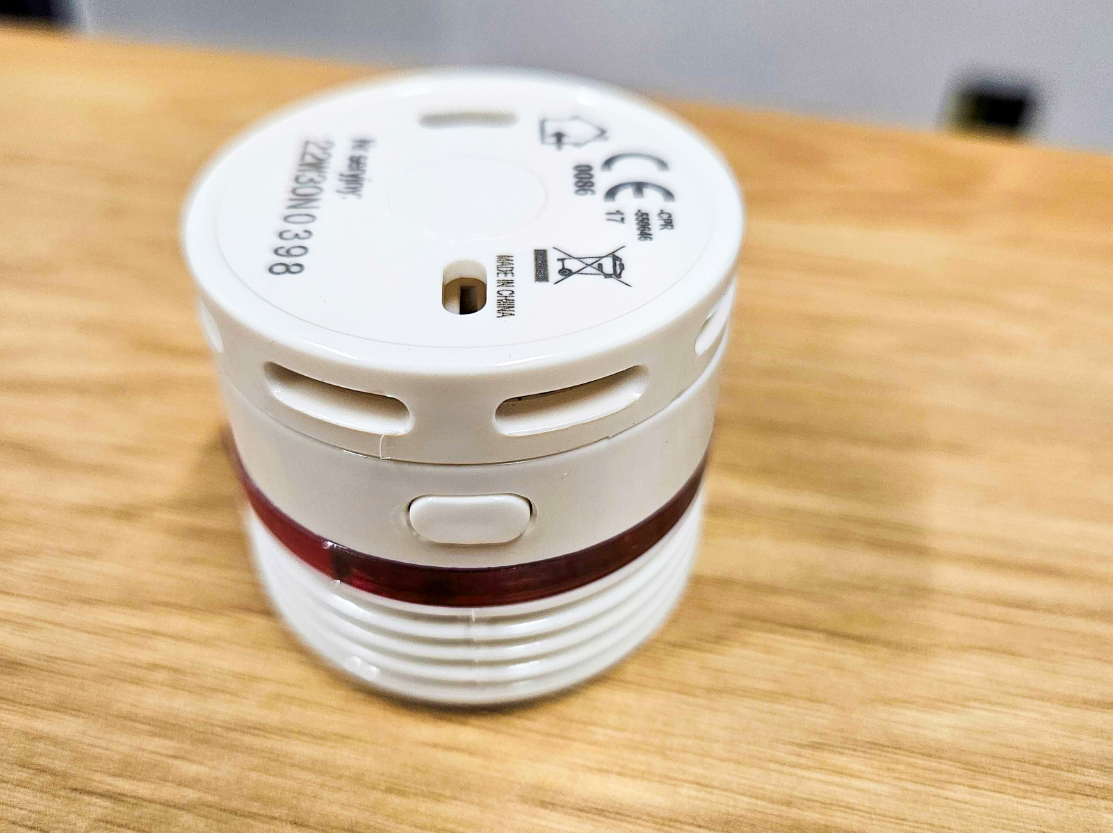 Zdjęcie przedtwia drewniany blat na którym leży biały czujnik czadu