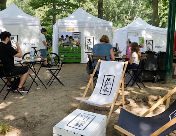 Zdjęcie z jednej z poprzednich edycji Jedzielni. Ludzie siedżą przy stolikacj i jedzą