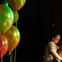 zdjęcie przedstawia po lewej stronie kolorowe balony, w prawym dolnym rogu muzyka grającego na kontrabasie