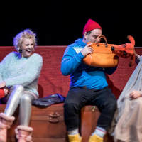 Zdjęcie ze spektaklu: trzy osoby siedzące na ławce. Mężczyzna trzyma przed sobą torebkę, zasłania się przed psem animowanym przez jedną z dwóch aktorek.