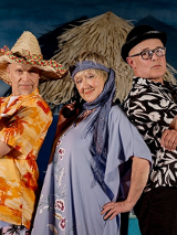 Dwóch mężczyzn i jedna kobieta, stoją obok siebie i patrzą w obiektyw. Ubrani sa w kolorowe stroje, jeden z mężczyzn trzyma mały pistolet.