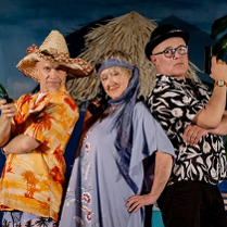 Dwóch mężczyzn i jedna kobieta, stoją obok siebie i patrzą w obiektyw. Ubrani sa w kolorowe stroje, jeden z mężczyzn trzyma mały pistolet.