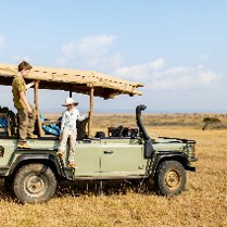 Otwarty samochód terenowy na sawannie, a na nim dwójka dzieci.