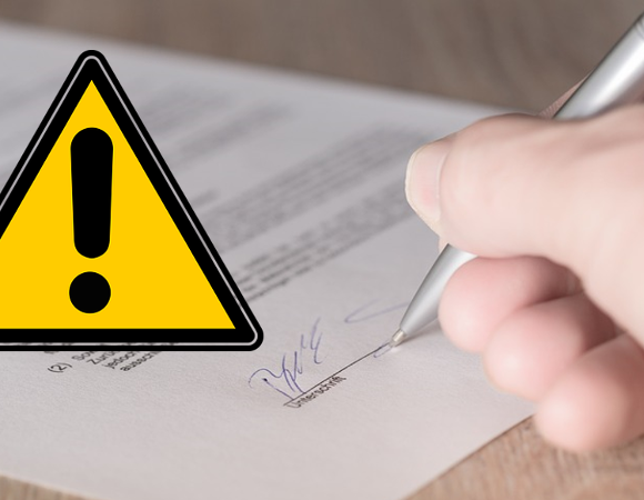 Ilustracja przedstawia dłoń podpisującą umowę oraz trójkątny znak ostrzegtawczy z wykrzyknikiem.
