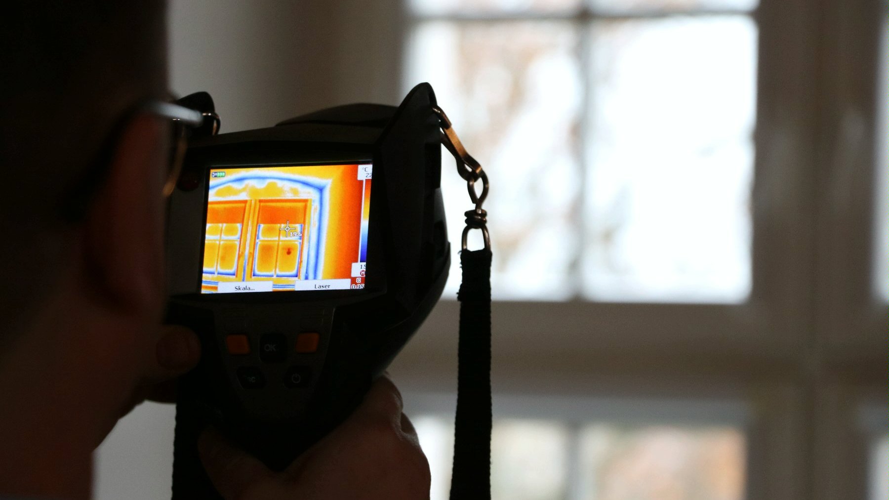 Zdjęcie przedstawia kamerę termowizyjną robiącą pomiar okna - grafika artykułu