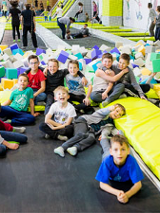 Baner: dzieci siedzą i leżą na trampolinach. w głębi miękkie kostki z pianki.