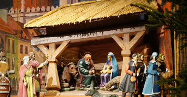 Szopka bożonarodzeniowa z figurkami Marii, Józefa, Jezusa i innych postaci biblijnych.