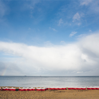 Plaża - obraz niebo, morze i piaszczysta plaża.Na plaży biało-czerwone parawany.