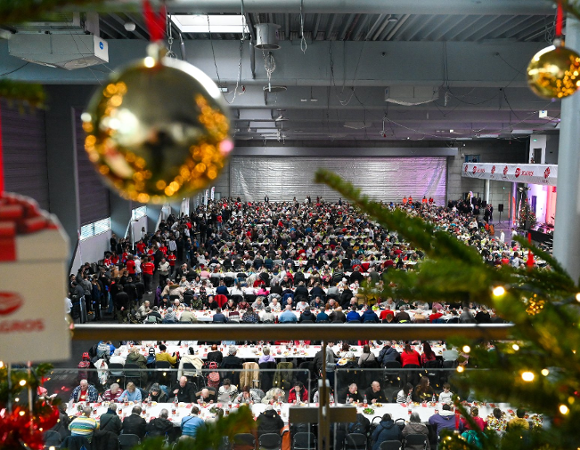 Widok na ludzi siedzących w hali MTP przy stołach podczas Wigilii Caritas